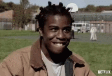 A Man With Dreadlocks Is Smiling In A Park With A Netflix Logo In The Corner GIF