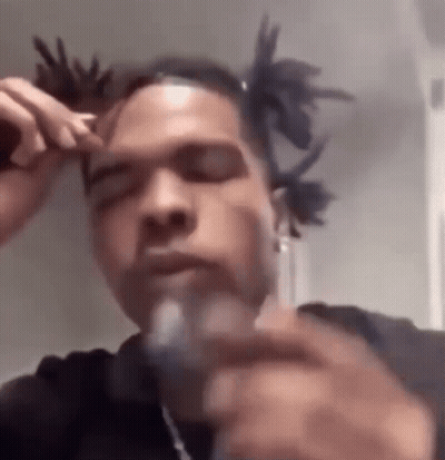 A Man With Dreadlocks Is Smoking A Cigarette While Wearing A Black Shirt . GIF