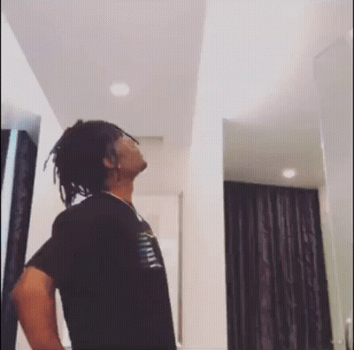 A Man With Dreadlocks Is Standing In A Room With His Hands On His Hips . GIF