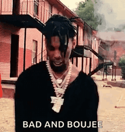 A Man With Dreadlocks Is Standing In Front Of A Brick Building . GIF