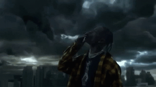 A Man With Dreadlocks Is Standing In Front Of A Cloudy Sky Looking Up . GIF