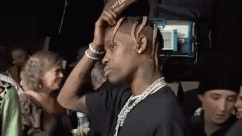 A Man With Dreadlocks Is Standing In Front Of A Crowd Of People . GIF