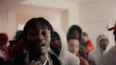 A Man With Dreadlocks Is Standing In Front Of A Crowd Of People Wearing Hoodies GIF