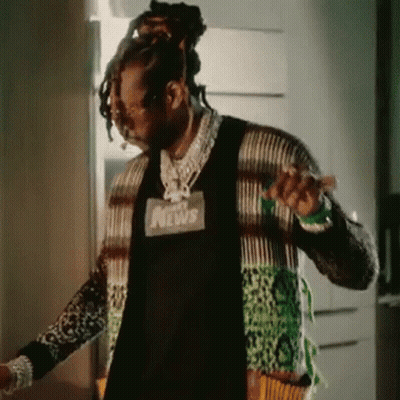 A Man With Dreadlocks Is Standing In Front Of A Door Wearing A Sweater . GIF