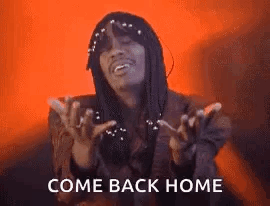 A Man With Dreadlocks Is Standing In Front Of A Red Background And Says `` Come Back Home '' With His Hands Outstretched GIF