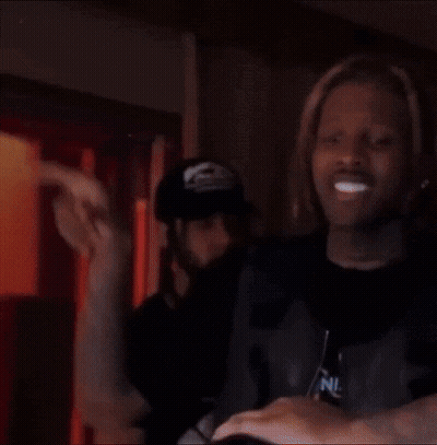 A Man With Dreadlocks Is Standing Next To A Woman In A Dark Room . GIF