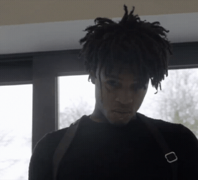 A Man With Dreadlocks Is Wearing A Black Shirt And A Black Bag GIF