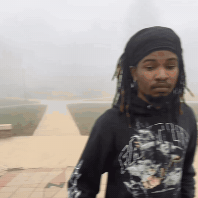 A Man With Dreadlocks Is Wearing A Black Shirt That Says ' Faith ' GIF