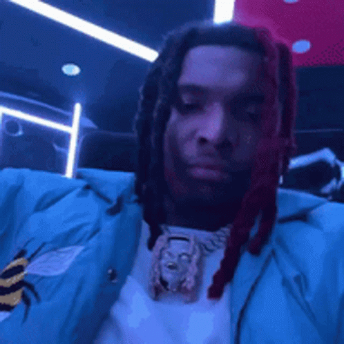 A Man With Dreadlocks Is Wearing A Blue Jacket . GIF