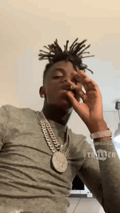 A Man With Dreadlocks Is Wearing A Chain Around His Neck And Smoking A Cigarette GIF