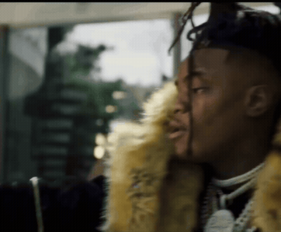 A Man With Dreadlocks Is Wearing A Fur Coat And Necklace . GIF