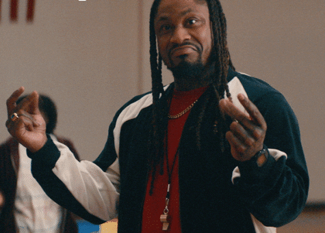 A Man With Dreadlocks Is Wearing A Red Shirt And A Black Jacket GIF