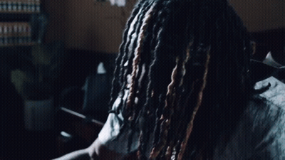 A Man With Dreadlocks Is Wearing A Shirt That Says Dior On It GIF