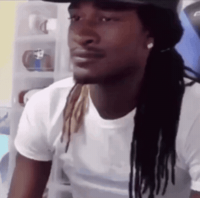A Man With Dreadlocks Is Wearing A White Shirt And A Black Hat . GIF