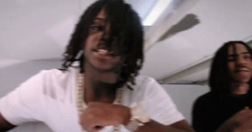 A Man With Dreadlocks Is Wearing A White Shirt And Gold Chains GIF