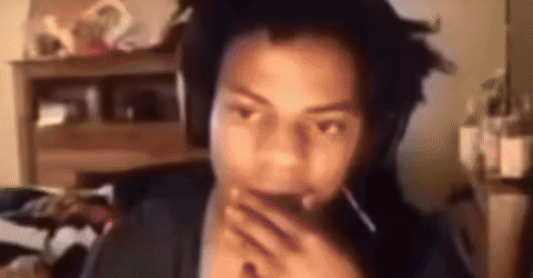 A Man With Dreadlocks Is Wearing Headphones And Covering His Mouth With His Hands . GIF