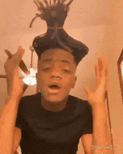 A Man With Dreadlocks On His Head Is Making A Funny Face With His Hands In The Air . GIF
