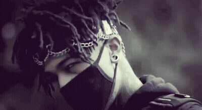 A Man With Dreadlocks Wearing A Black Mask And Chains Around His Head GIF