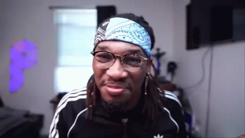 A Man With Dreadlocks Wearing Glasses And A Bandana On His Head . GIF