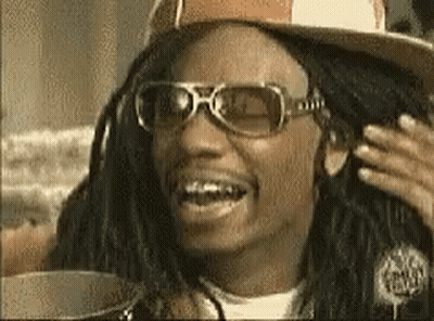 A Man With Dreadlocks Wearing Sunglasses And A Hat Is Smiling GIF
