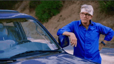 A Man With Glasses And A Bandage On His Head Leans On A Car GIF