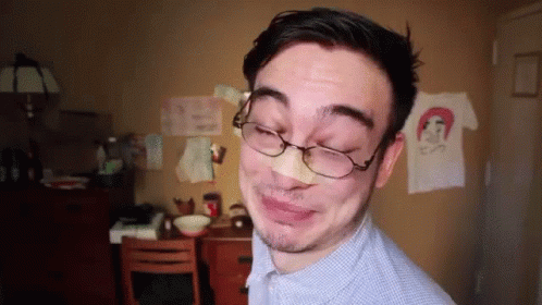 A Man With Glasses And A Bandage On His Nose Making A Funny Face GIF