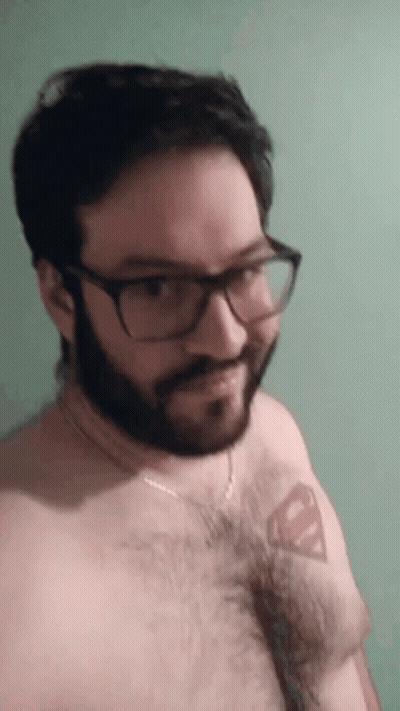 A Man With Glasses And A Beard Has A Superman Tattoo On His Chest GIF