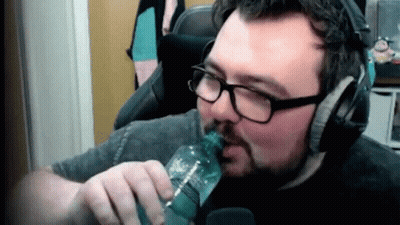 A Man With Glasses And A Beard Is Drinking From A Bottle . GIF