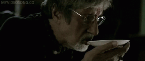 A Man With Glasses And A Beard Is Drinking From A White Bowl With The Words Myvideosong.co Written On The Bottom GIF