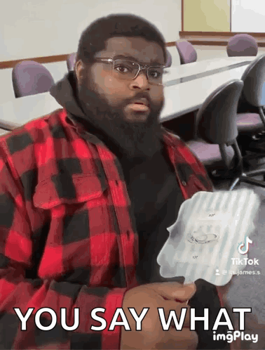A Man With Glasses And A Beard Is Holding A Piece Of Paper That Says " You Say What " GIF