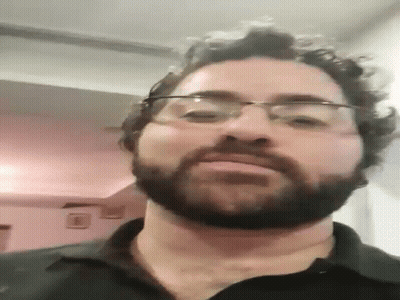 A Man With Glasses And A Beard Is Looking At The Camera . GIF
