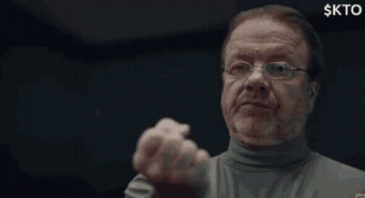 A Man With Glasses And A Beard Is Making A Funny Face With His Fist In The Air . GIF
