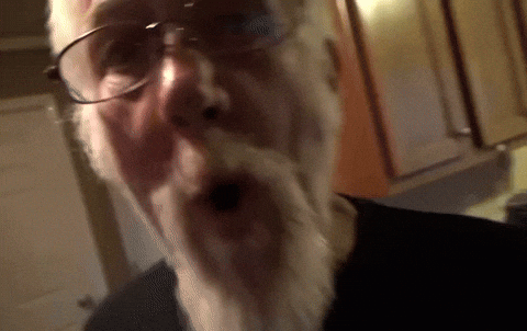 A Man With Glasses And A Beard Is Making A Surprised Face GIF