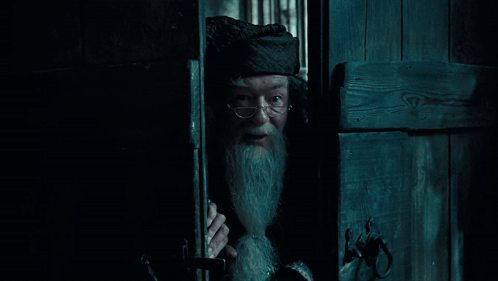 A Man With Glasses And A Beard Is Peeking Out Of A Doorway GIF