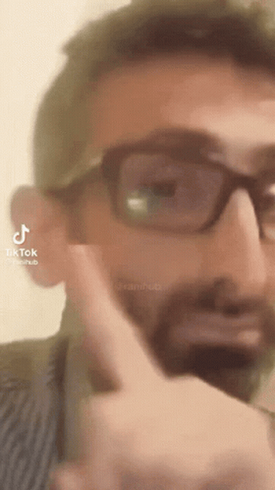 A Man With Glasses And A Beard Is Pointing His Finger At Something . GIF