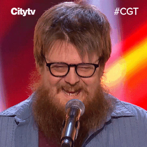 A Man With Glasses And A Beard Is Singing Into A Microphone With The Hashtag #Cgt GIF