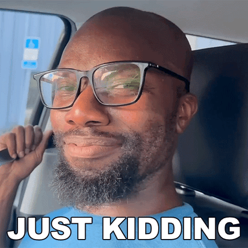 A Man With Glasses And A Beard Is Sitting In A Car With Just Kidding Written On The Bottom GIF