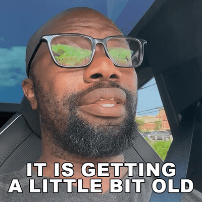 A Man With Glasses And A Beard Is Sitting In A Car With The Words It Is Getting A Little Bit Old Below Him GIF