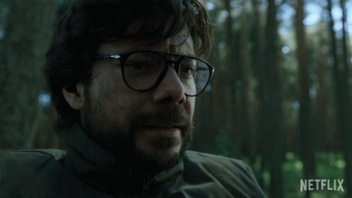 A Man With Glasses And A Beard Is Sitting In A Forest With A Netflix Logo In The Background GIF