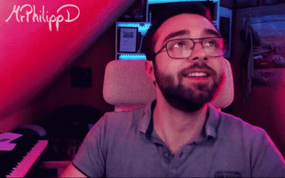 A Man With Glasses And A Beard Is Sitting In Front Of A Keyboard With The Name Mr. Philippd Written On It GIF