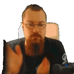 A Man With Glasses And A Beard Is Sitting In Front Of A Microphone With The Letter I On It Sticker