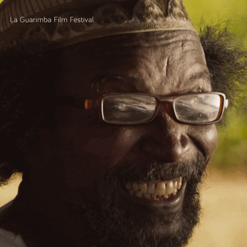 A Man With Glasses And A Beard Is Smiling And The Words La Guarimba Film Festival Are Above Him GIF