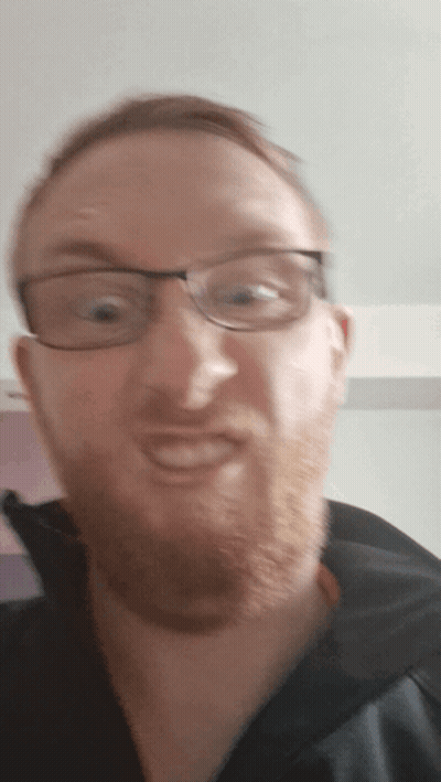 A Man With Glasses And A Beard Is Smiling For The Camera GIF