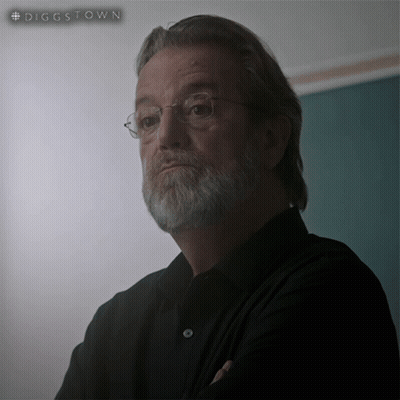 A Man With Glasses And A Beard Is Standing In Front Of A Green Board That Says #Diggstown GIF