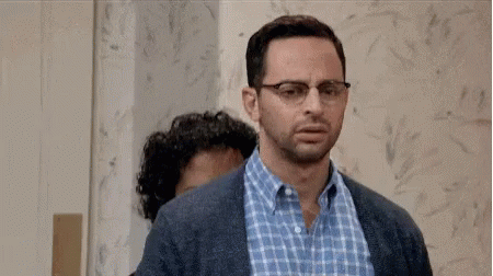 A Man With Glasses And A Beard Is Standing Next To Another Man With Glasses And A Beard . GIF