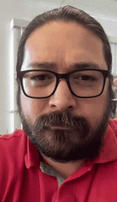 A Man With Glasses And A Beard Is Wearing A Red Polo Shirt GIF