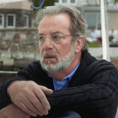 A Man With Glasses And A Beard Is Wearing A Sweater And A Blue Shirt GIF