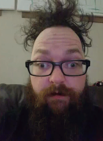 A Man With Glasses And A Beard Makes A Surprised Face GIF