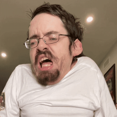 A Man With Glasses And A Beard Making A Face GIF