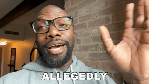 A Man With Glasses And A Beard Says Allegedly In Front Of A Brick Wall GIF